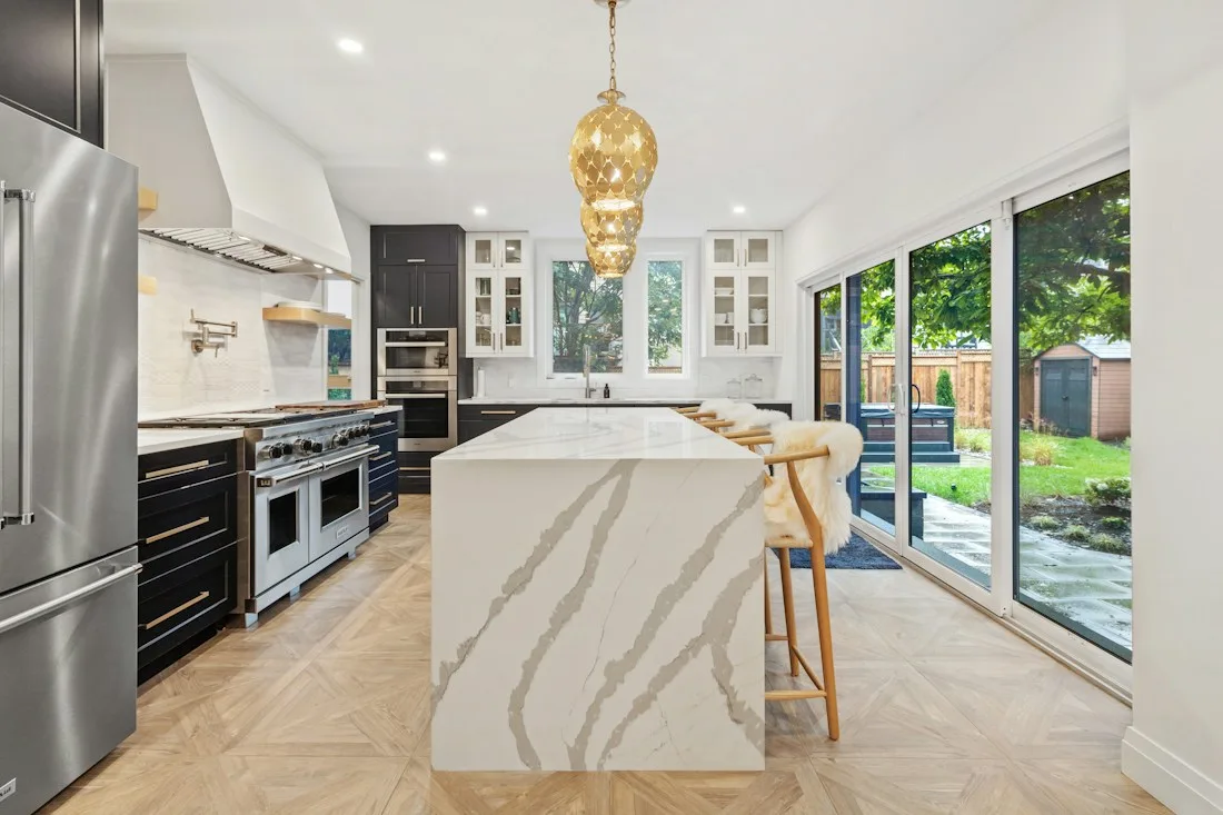 Cozinha remodelada com ilha em mármore e candeeiro dourado